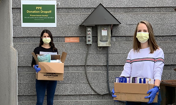 Woman wearing face masks and gloves carrying boxes of PPE to donate