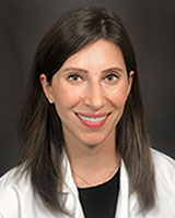 Headshot of Barnara Decker, MD, sitting against a grey background. She has medium length dark brown hair and is wearing her white coat.