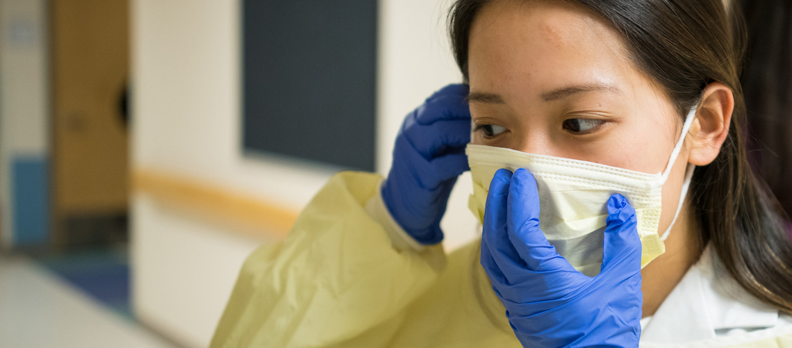 Nurse putting disposable face mask on.