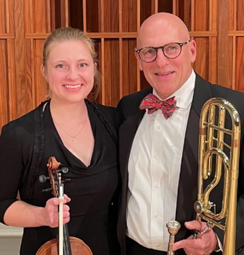 Jeffrey Peipert, MD, PhD holding a trombone, standing with colleague holding violin