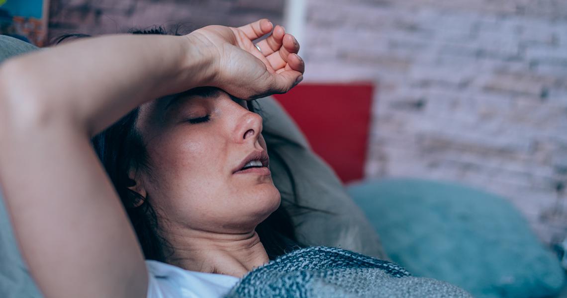 Woman lying on the couch suffering from a migraine.