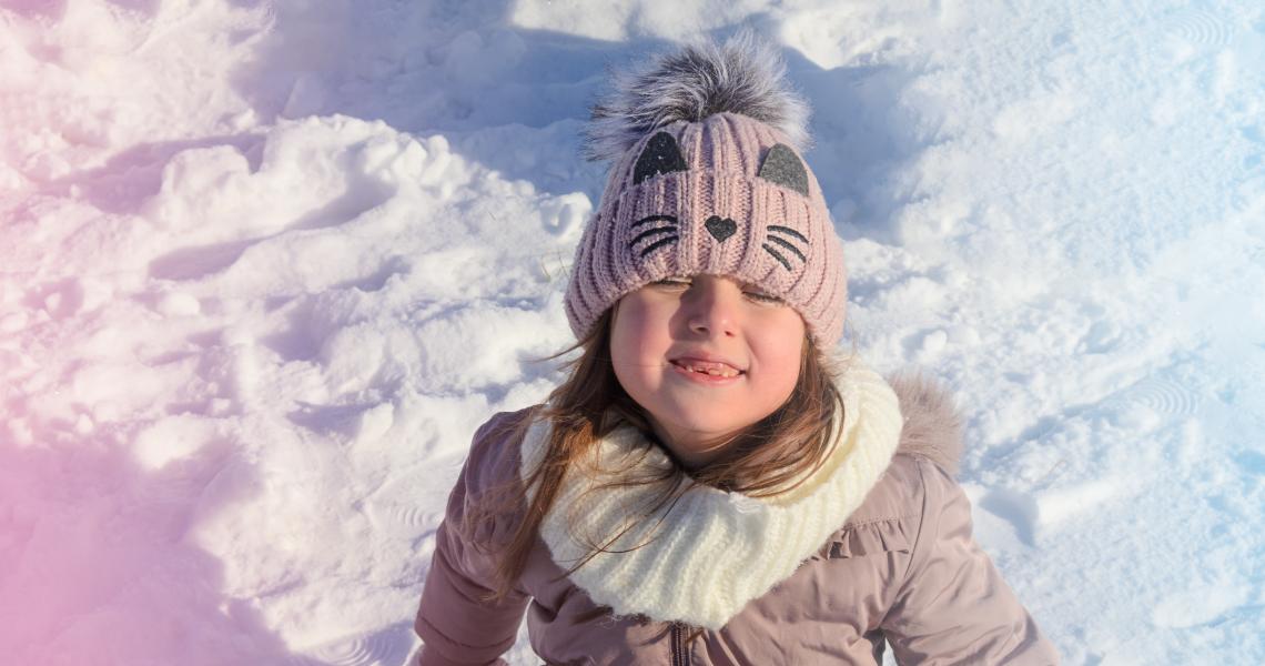 Child dressed in winter clothing playing in the snow.