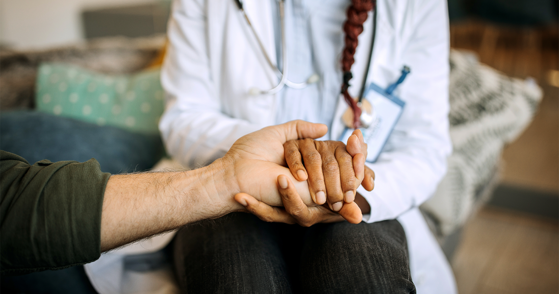 Provider holds a patients hand.