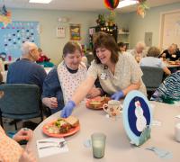 Nurse serving three seniors dinner.