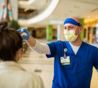 Staff in bright blue scrubs, taking temperatures in UVM Medical Center lobby