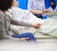Hospital visitor holding patient's hand