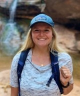 Alisha Booms, DO posing in front of a waterfall. 