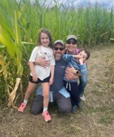 Alexandra Messerli, MD, poses with husband and her two children in a corn field.