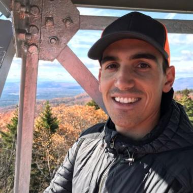Maguire Testimonial Photo, hat, jacket, outdoors.
