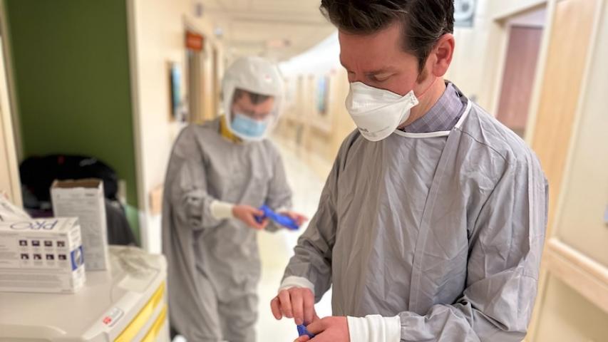 Gowned and masked providers putting on gloves at UVM Medical Center. 