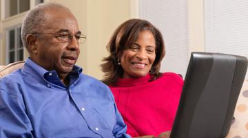 Older couple looking at a laptop while sitting on the couch.